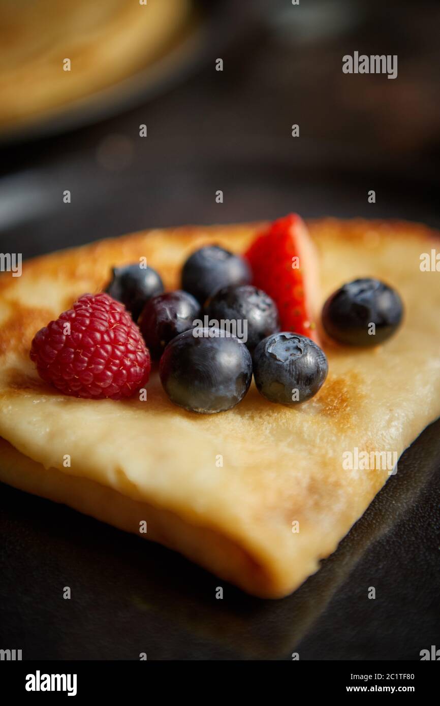 Chiudere fino a pancake con frutta fresca topping posto su scuro tavolo arrugginita Foto Stock