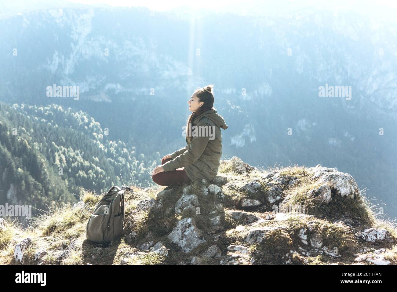 Una ragazza in solitudine si siede sulla cima di una montagna con gli occhi  chiusi e medita, o è alla ricerca di un'anima o di una consapevolezza. La  luce del sole cade