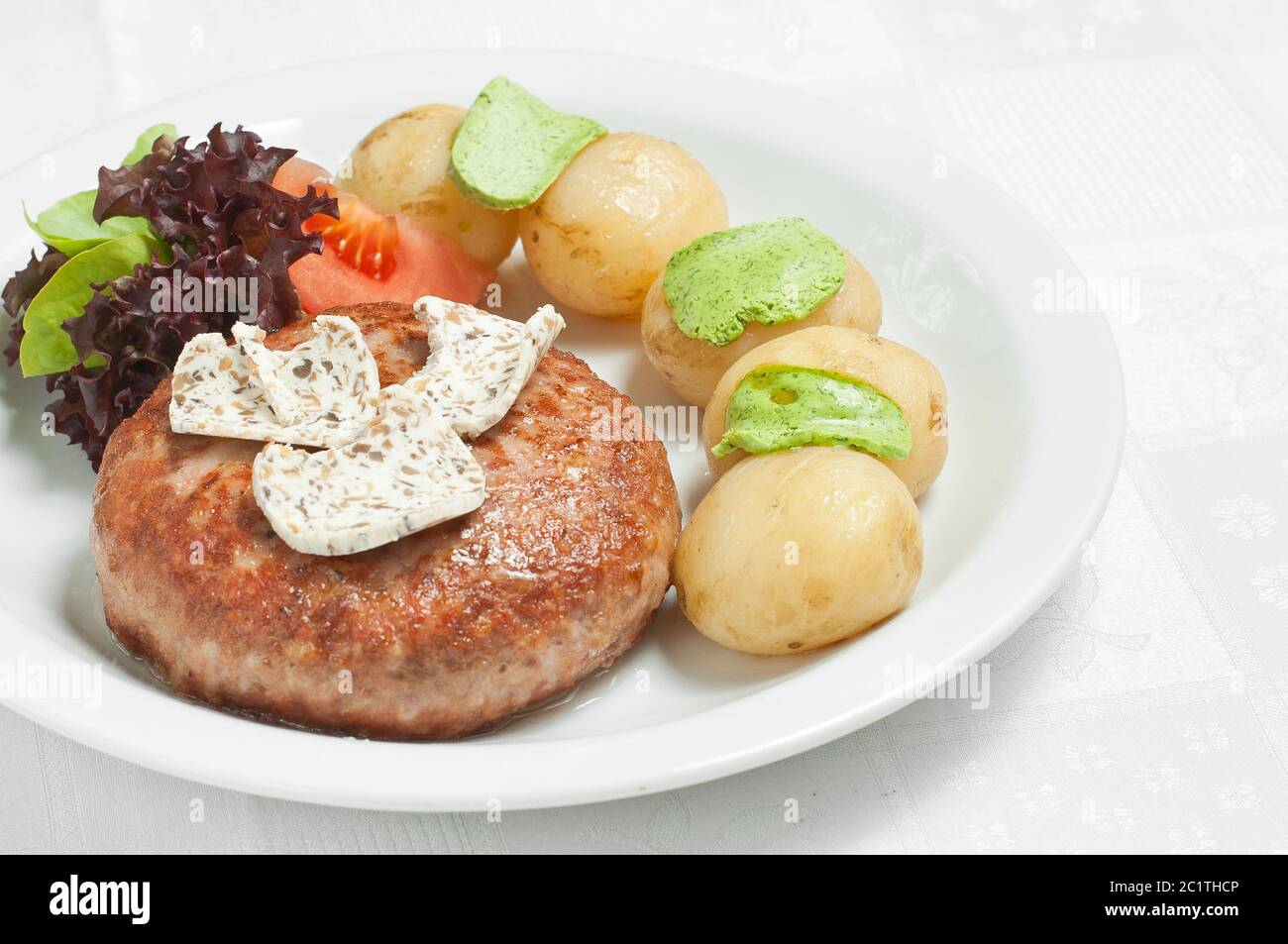 Cotoletta di carne con patate bollite e verdure su un piatto bianco. Foto Stock