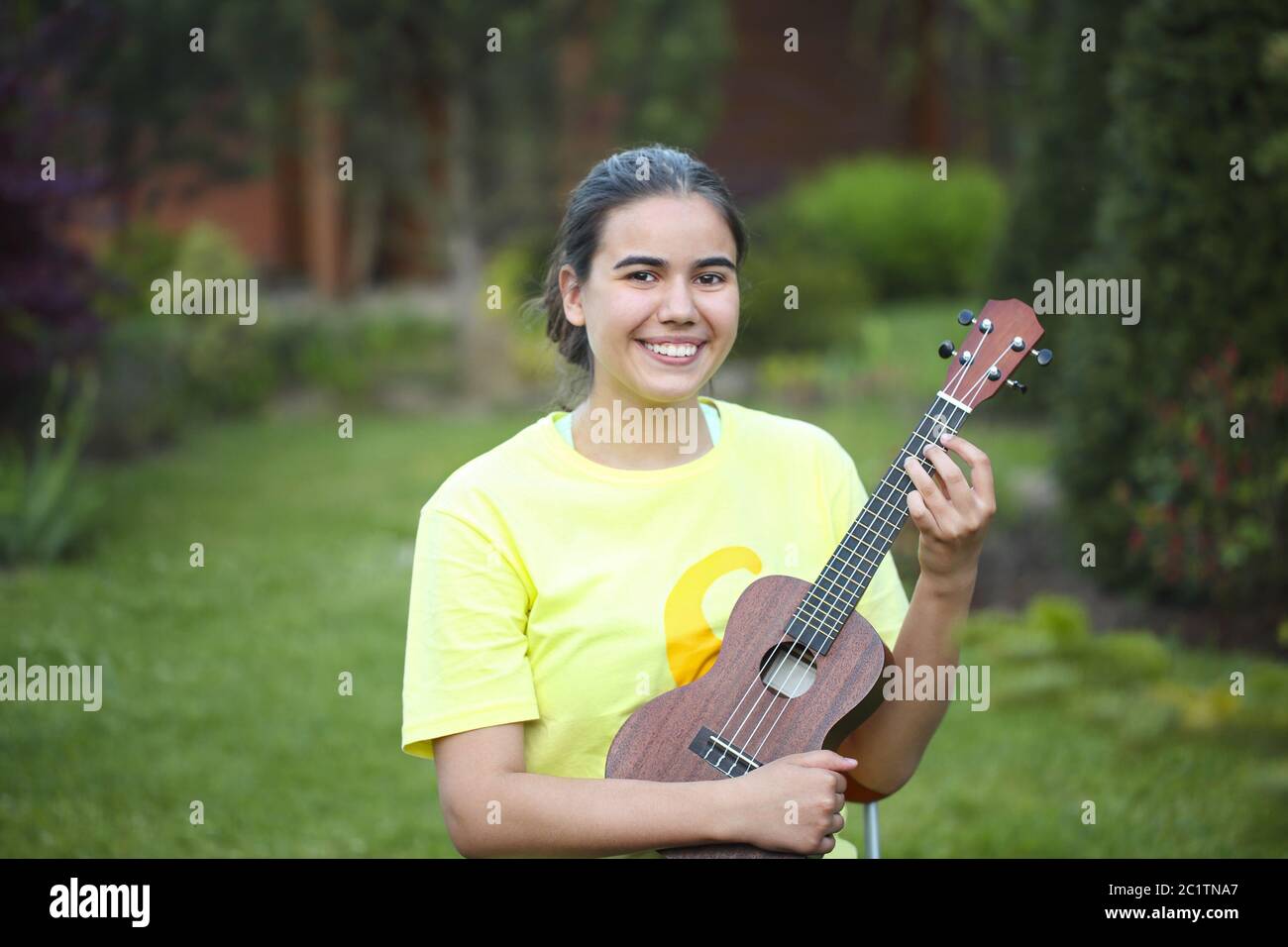 Cute ragazza teen che gioca il suo ukulele all'aperto Foto Stock