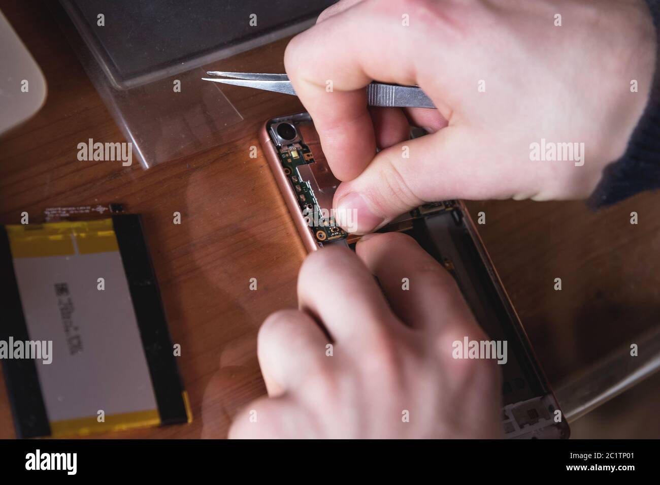 Primo piano della mano di un artigiano domestico che ripara uno smartphone smontato. Il concetto di elettronica autoriparante a casa Foto Stock