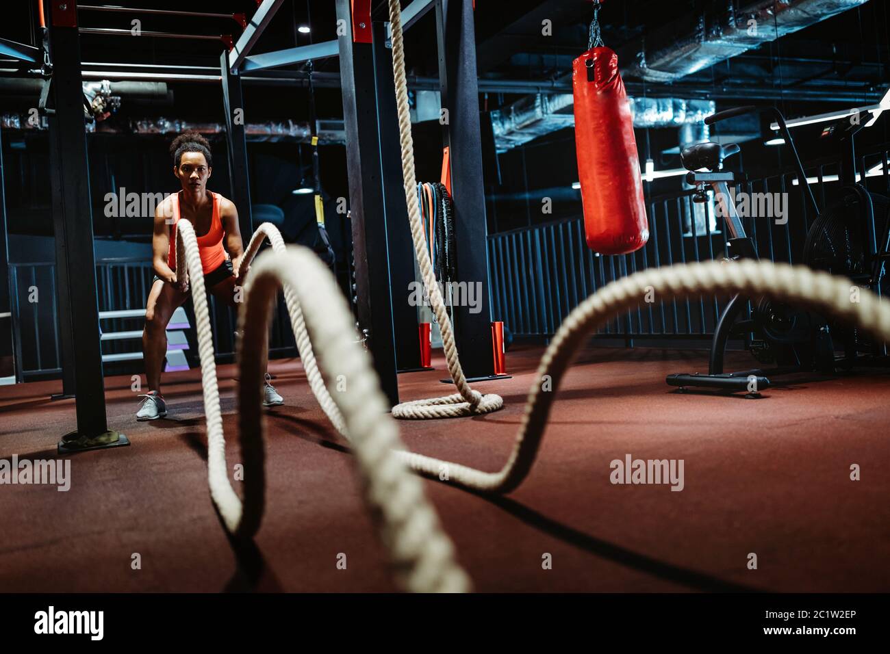 Potente attraente ragazza battaglia corda allenamento in palestra Foto Stock