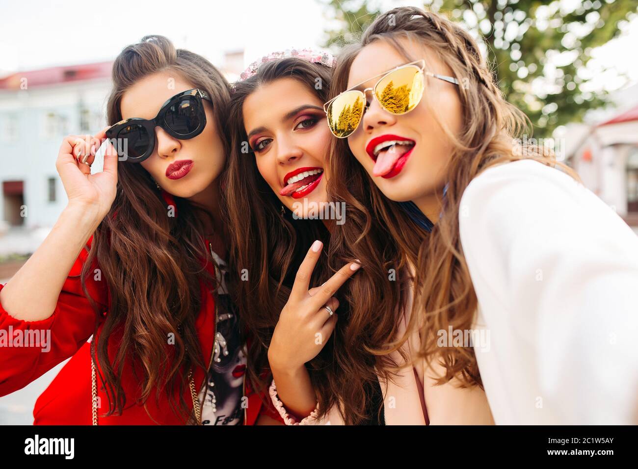 Belle ragazze in occhiali da sole che mostra segni di pace in telecamera con sorriso. Foto Stock