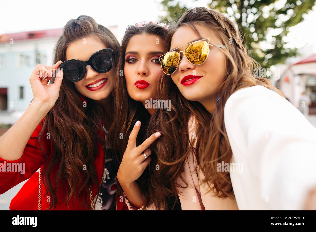 Belle ragazze in occhiali da sole che mostra segni di pace in telecamera con sorriso. Foto Stock