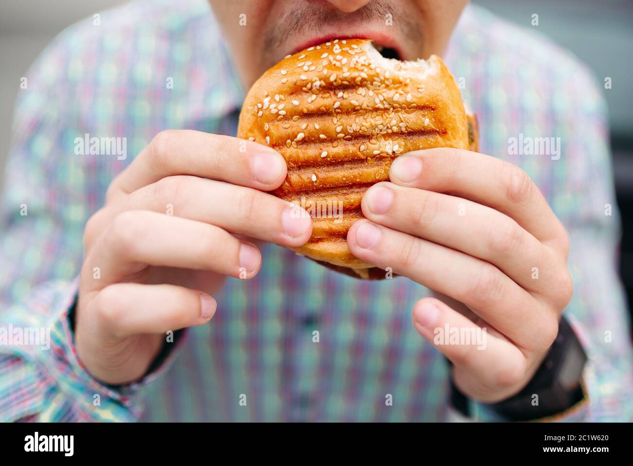 Irriconoscibile uomo mangiare hamburger deliziosi con pane grigliato Foto Stock