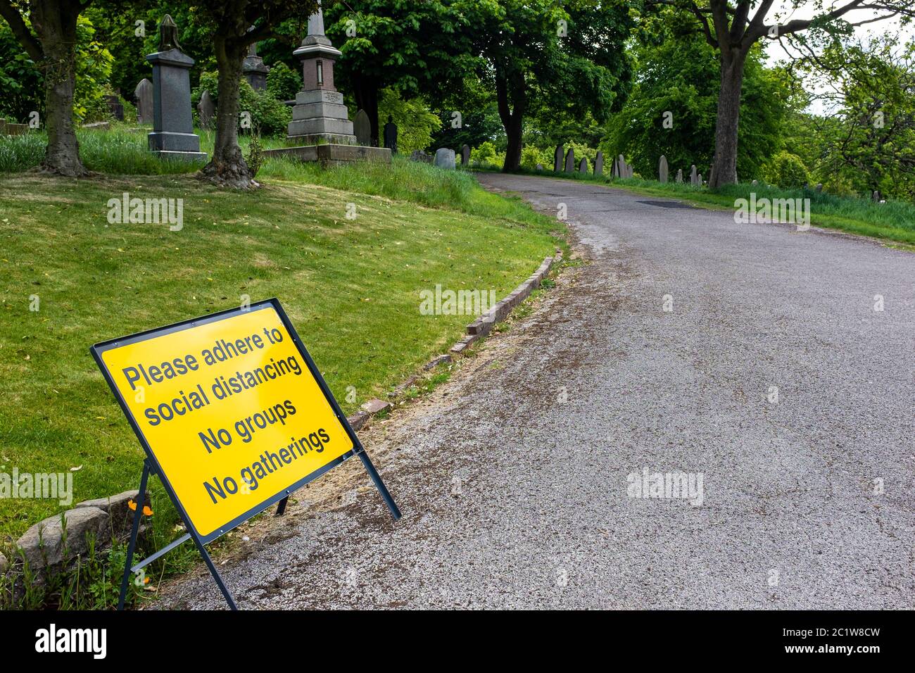 Accedi a un cimitero dicendo "si prega di aderire a distanza sociale, nessun gruppo, nessun incontro" Foto Stock