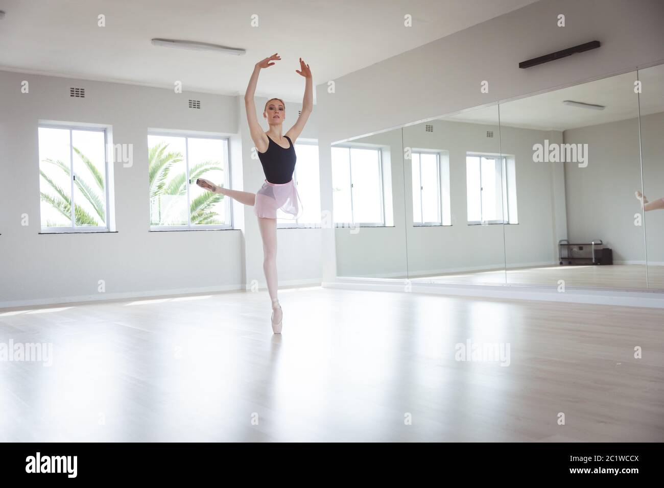 Ballerina caucasica femminile che si concentra sul suo esercizio con le braccia sopra la testa Foto Stock