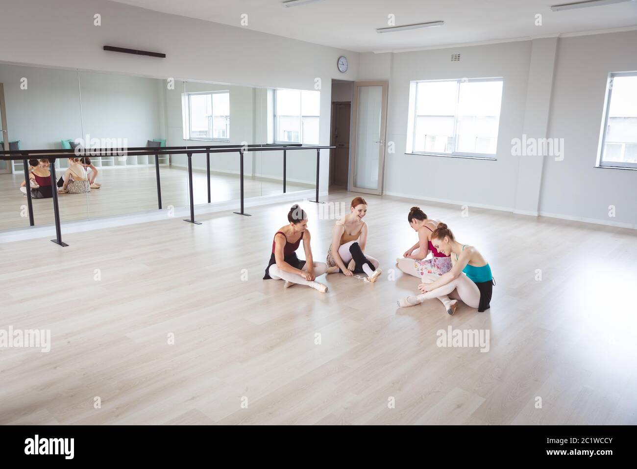 Ballerine caucasiche femminili di balletto che hanno una conversazione in un luminoso studio di balletto e che sono felici Foto Stock