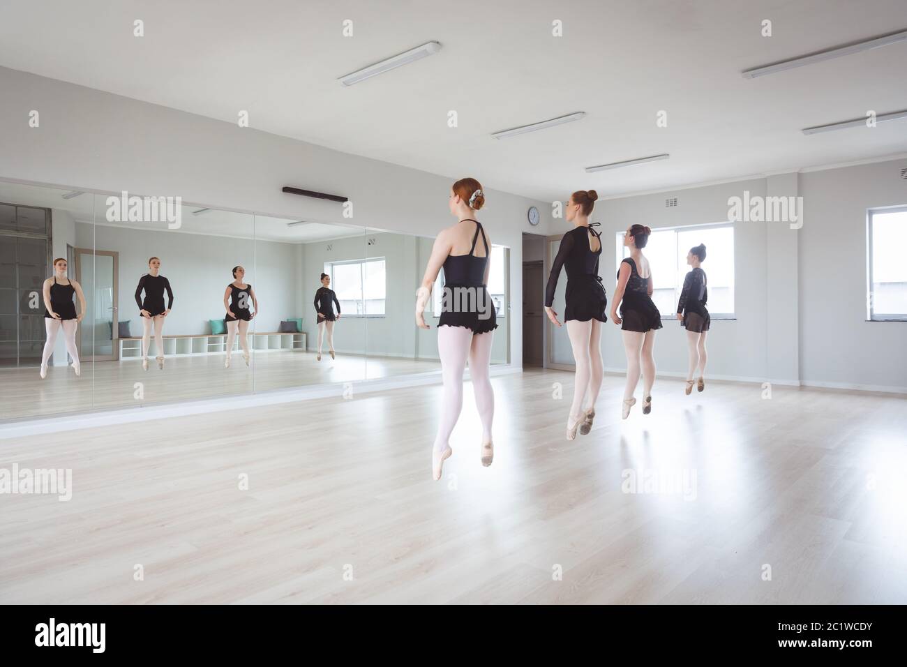 Ballerine caucasiche di balletto in tute nere che si esercitano durante una classe Foto Stock