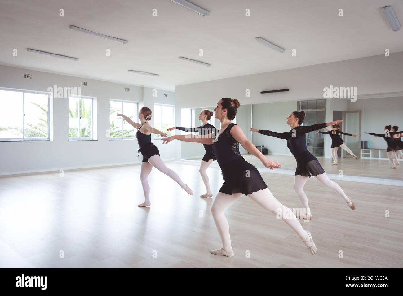 Ballerini caucasici in tute nere che si esercitano durante una lezione di balletto Foto Stock