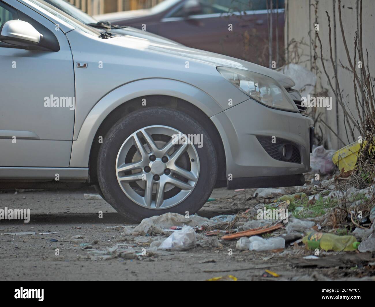 auto color argento parcheggiata accanto alla spazzatura Foto Stock
