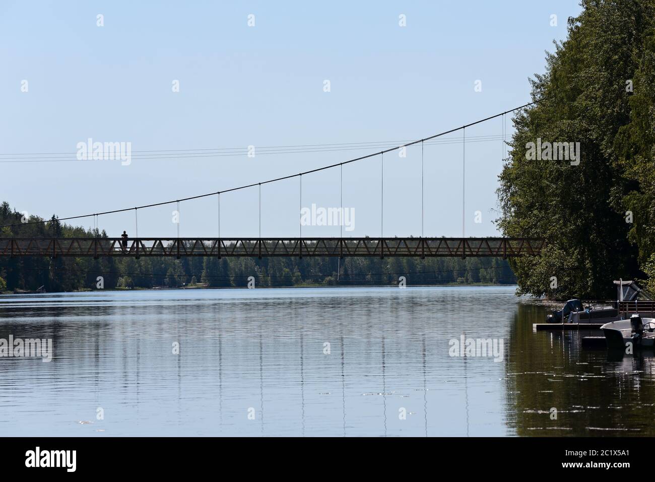 Un lungo ponte di cavo su un fiume soleggiato Foto Stock