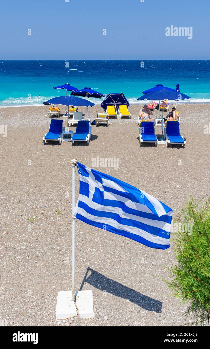 Bandiera greca di fronte ai lettini sulla spiaggia di Rodi, Isola di Rodi, Grecia Foto Stock