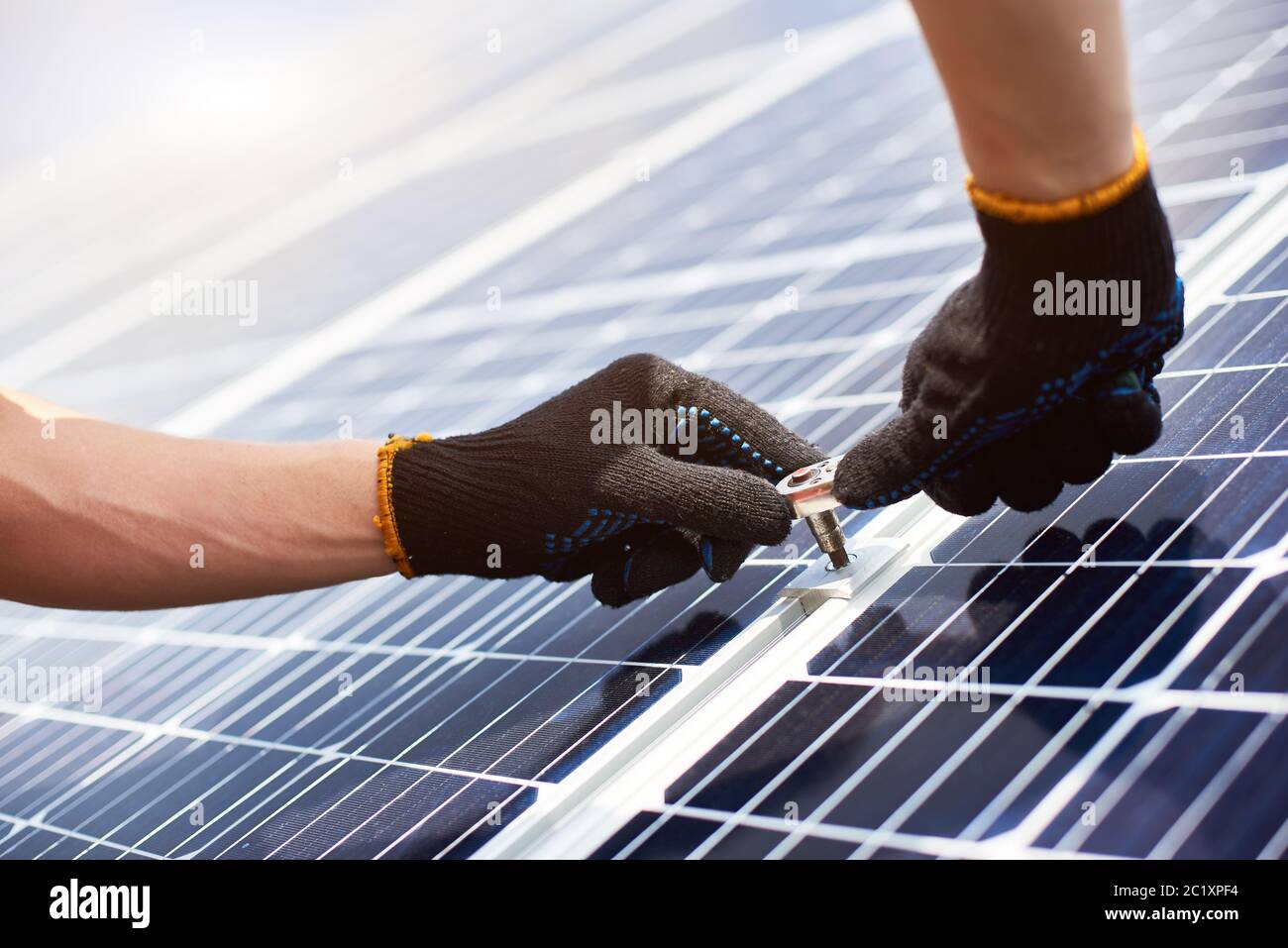 Primo piano di mani mans in guanti neri con chiave nelle mani che installa pannelli solari. Concetto: Energia rinnovabile, tecnologia, elettricità, servizio, energia verde. Foto Stock