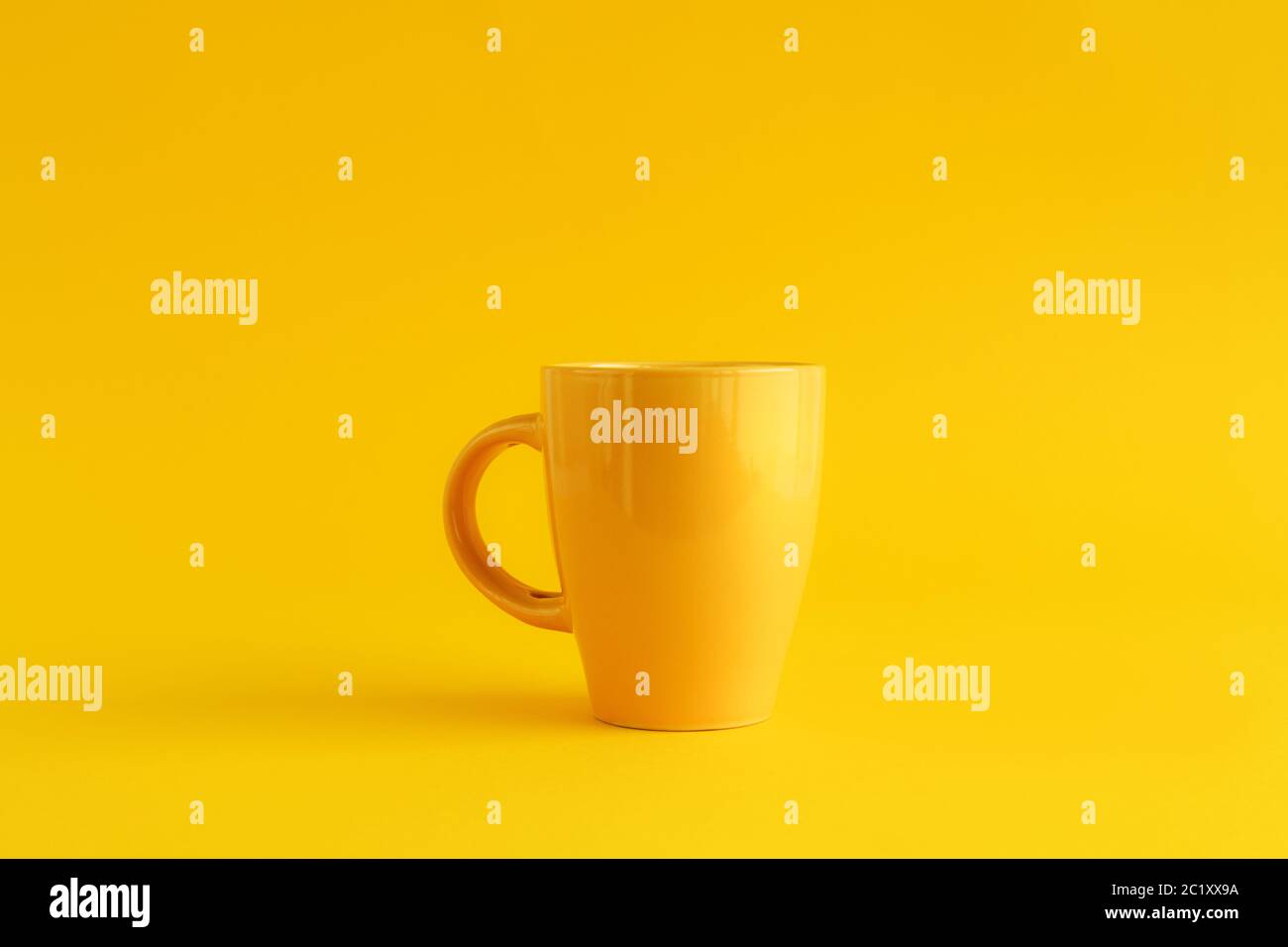 Tazza da caffè gialla singola su sfondo giallo, pausa caffè e concetto di dipendenza da caffeina Foto Stock