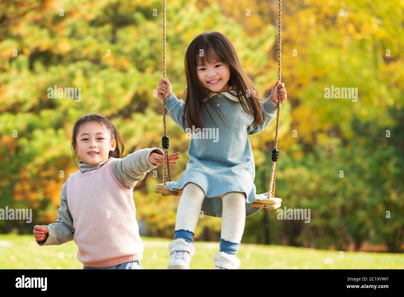 Due ragazze giocano su un'oscillazione nel parco Foto Stock