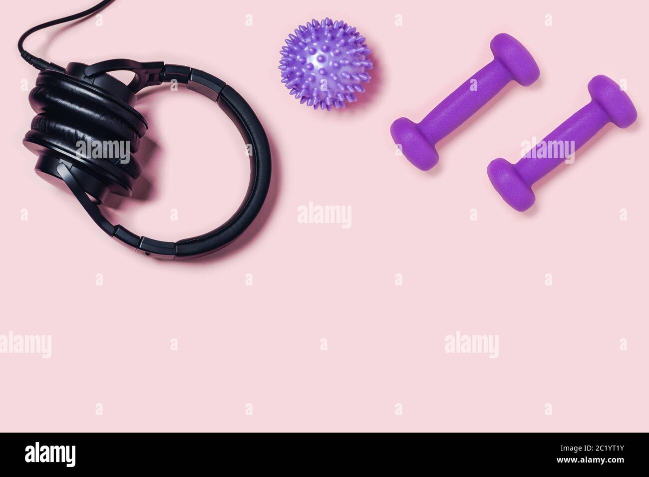 Sneakers, manubri e pallina da massaggio su sfondo rosa. Foto Stock