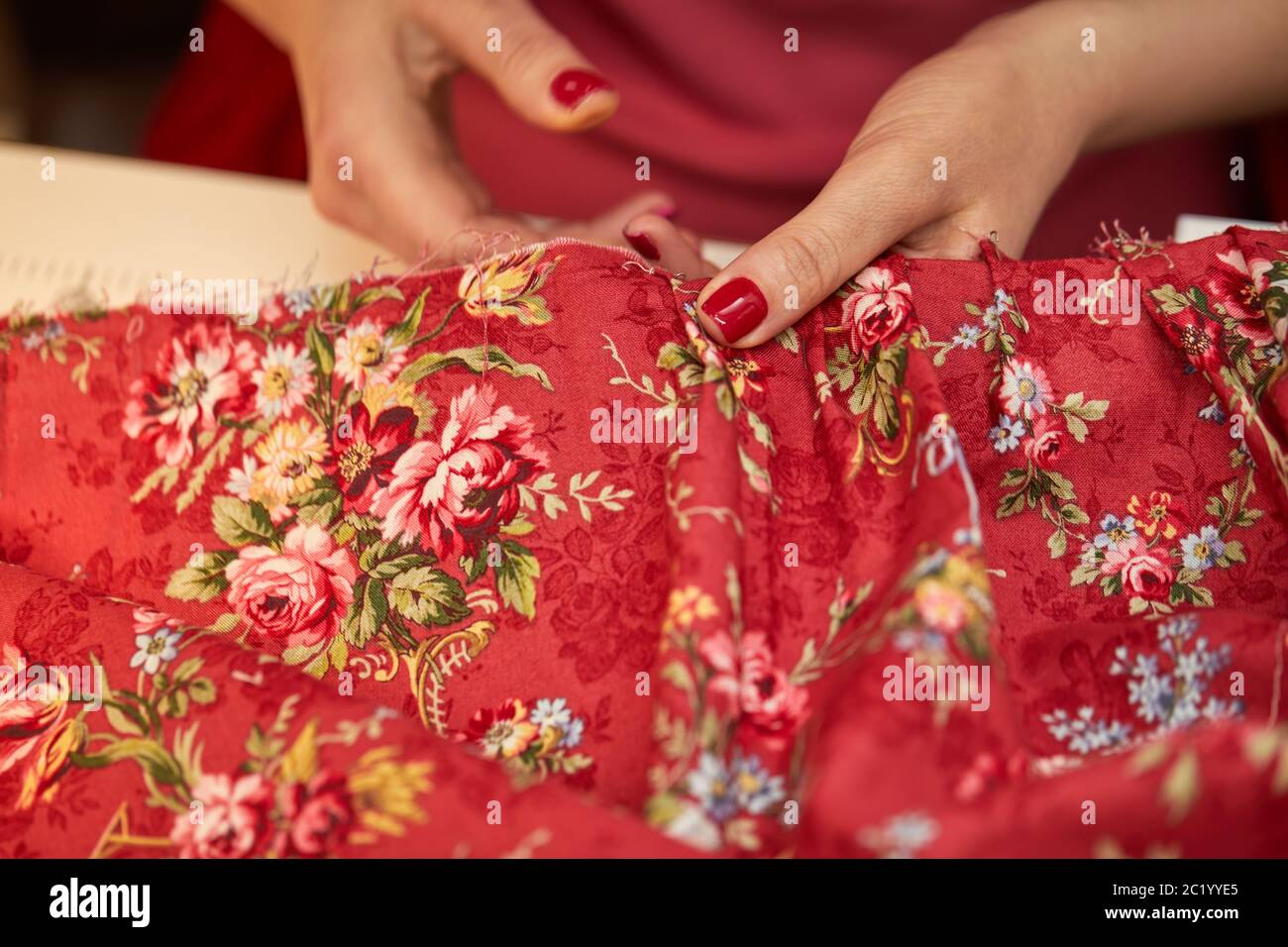 donna sarto indossa un abito rosso. Lavorare su misura nel suo negozio su misura Foto Stock