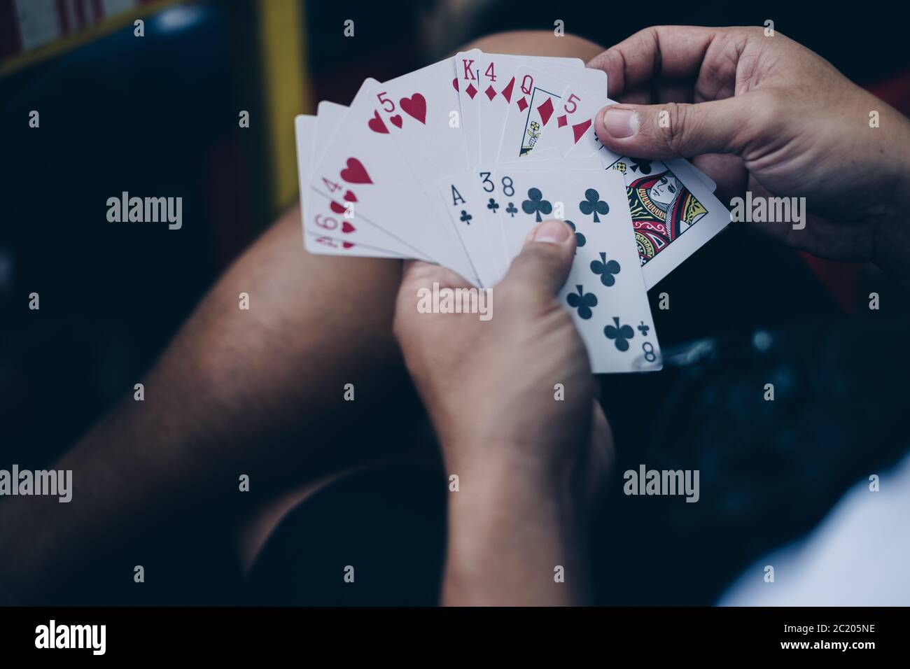 Mani che organizzano le carte da gioco trattate in un gioco di poker. Messa a fuoco selettiva. Foto Stock