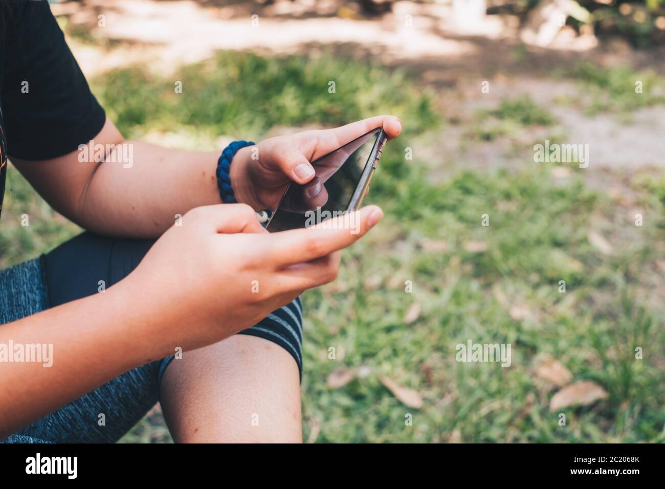 La ragazza gioca a giocare, usa i social media e naviga in rete utilizzando un telefono cellulare in ambiente esterno. Messa a fuoco selettiva. Spazio di copia. Foto Stock