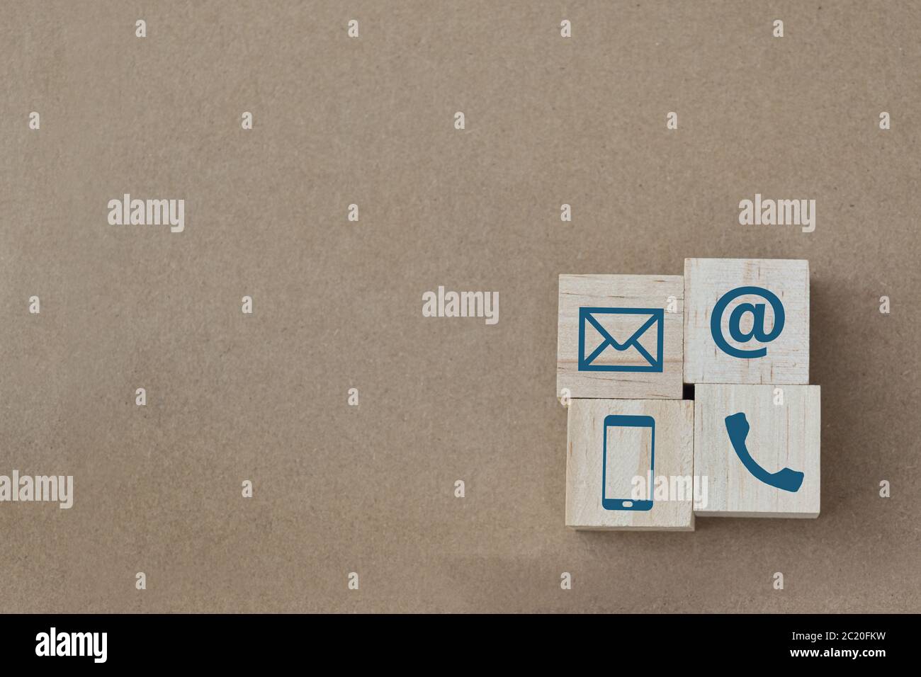 Cubo di legno con icone di Telefono, e-mail e posta su sfondo di carta marrone. Spazio di copia. Contattaci. Foto Stock