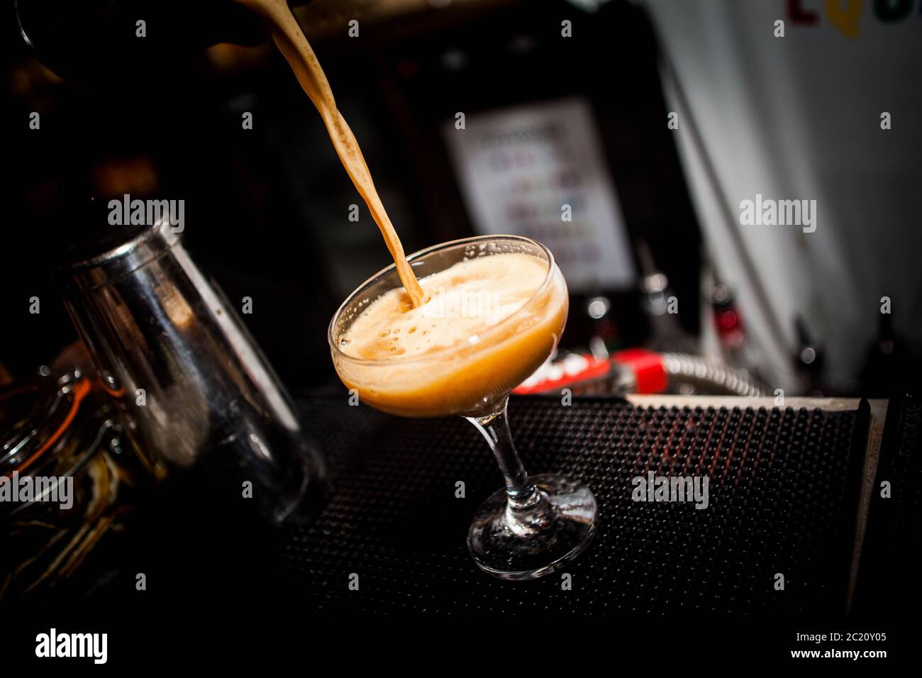 Cocktail alcolico all'arancia versato in bicchiere Foto Stock