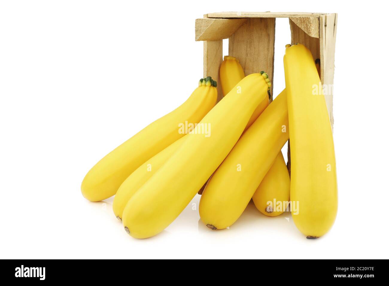 zucchine gialle in una cassa di legno su sfondo bianco Foto Stock