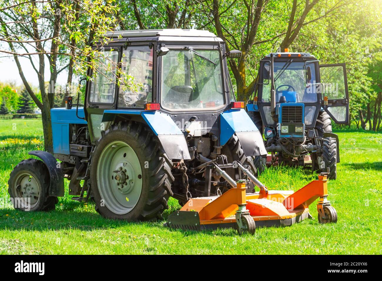 Il trattore utilizza un rasaerba trainato per falciare l'erba sui prati cittadini Foto Stock