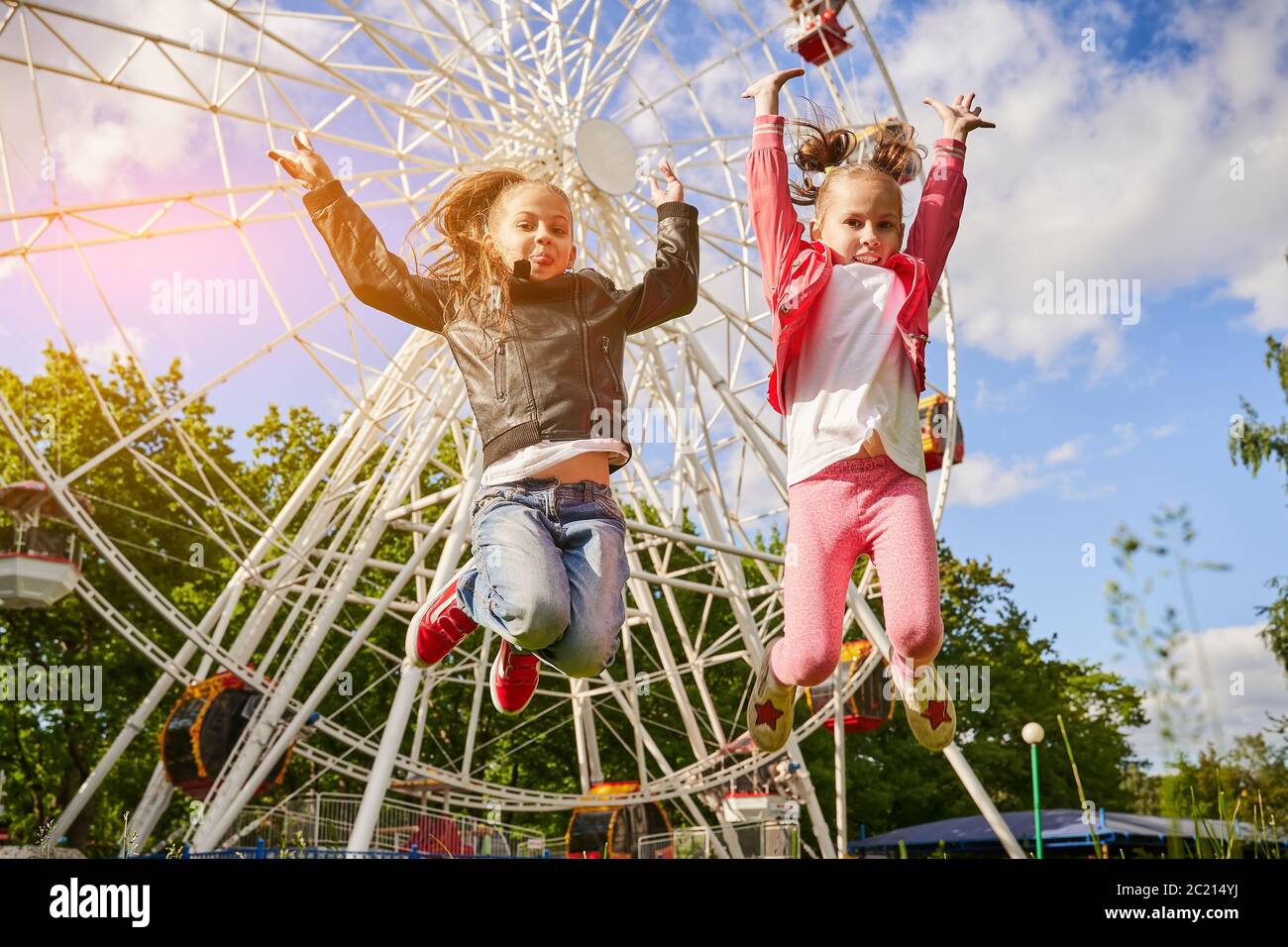 Due ragazze si divertono nel parco divertimenti. Una ruota panoramica è sullo sfondo. Foto Stock