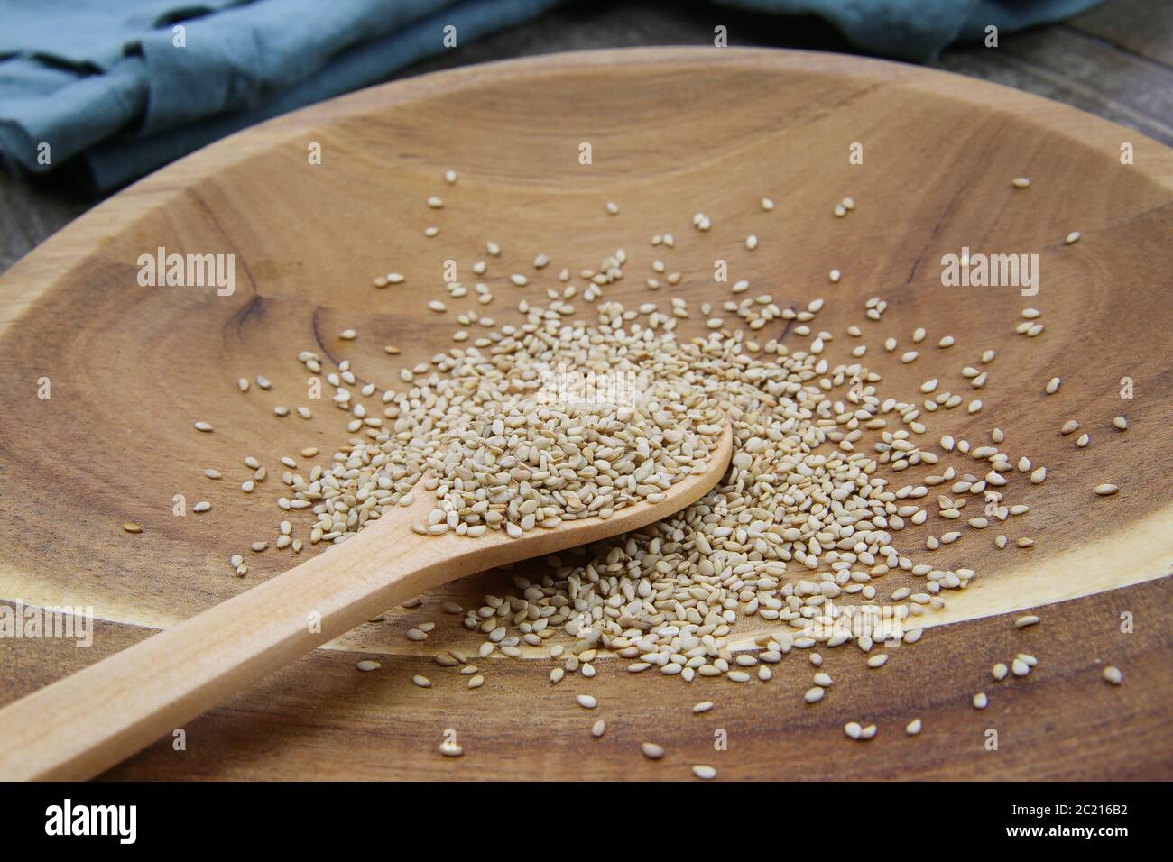 Primo piano di semi di sesamo grezzi isolati su cucchiaio e piastra di legno Foto Stock