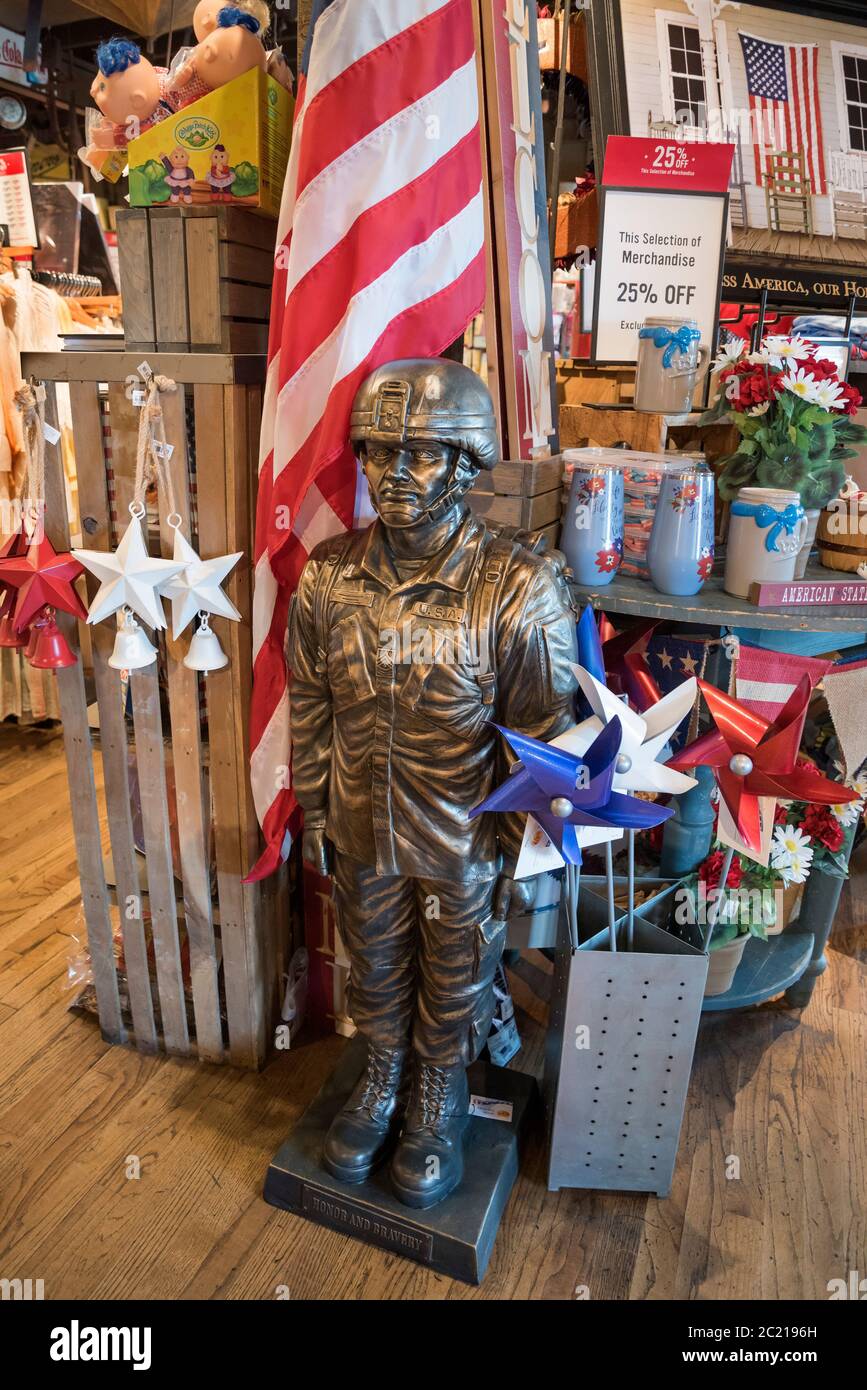 Statua all'aperto e bandiera di un soldato militare statunitense costruito in pietra di fusione con finitura in bronzo per la vendita presso un ristorante e negozio Cracker Barrel Foto Stock