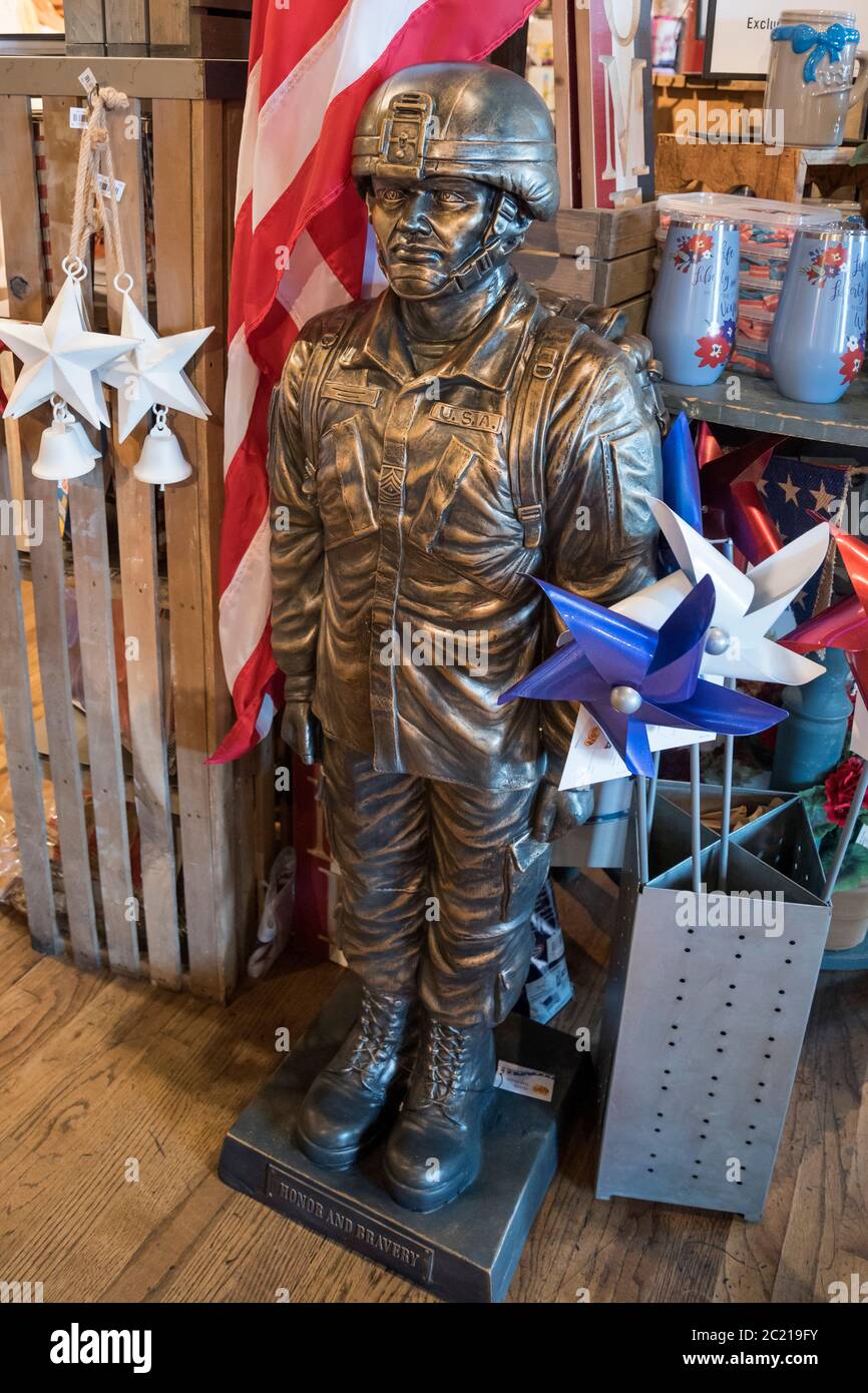 Statua all'aperto e bandiera di un soldato militare statunitense costruito in pietra di fusione con finitura in bronzo per la vendita presso un ristorante e negozio Cracker Barrel Foto Stock