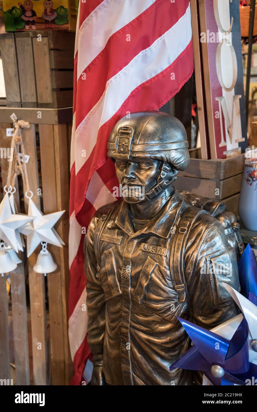Statua all'aperto e bandiera di un soldato militare statunitense costruito in pietra di fusione con finitura in bronzo per la vendita presso un ristorante e negozio Cracker Barrel Foto Stock
