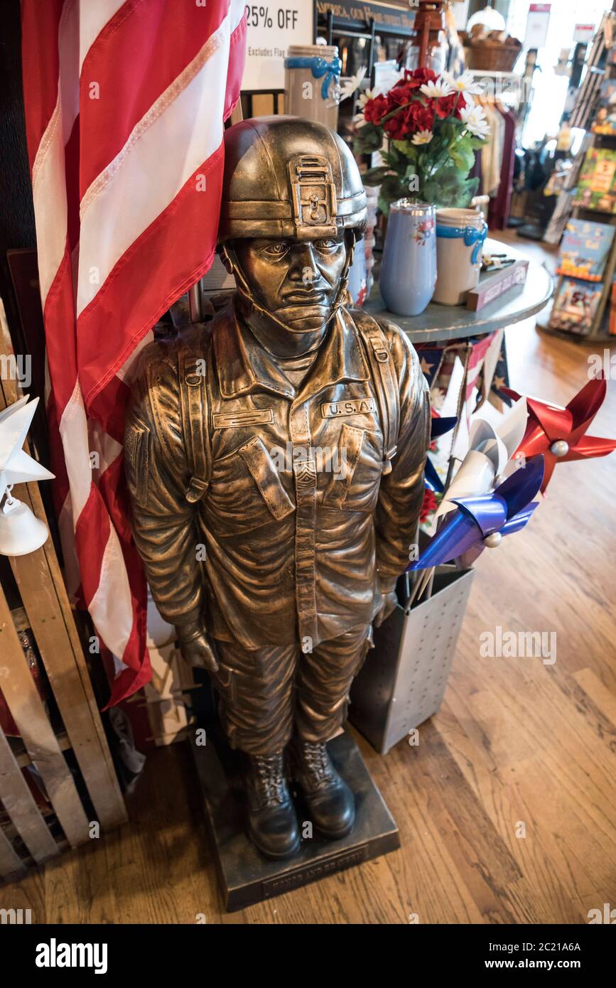 Statua all'aperto e bandiera di un soldato militare statunitense costruito in pietra di fusione con finitura in bronzo per la vendita presso un ristorante e negozio Cracker Barrel Foto Stock