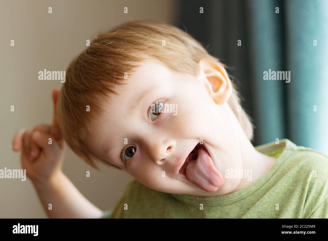 Bel ragazzo che mostra la lingua. Il bambino mette fuori la lingua - primo piano. Foto Stock