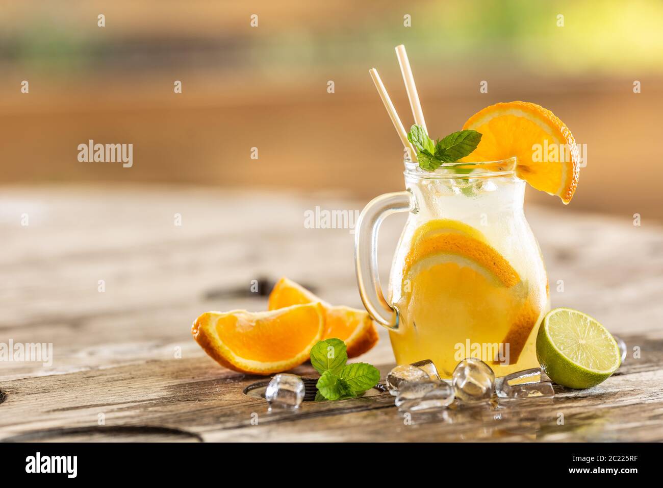 Rinfrescante vaso di limonata d'arancia con ghiaccio, menta, paillette di carta e spicchi di arancia fresca e lime sul lato. Foto Stock