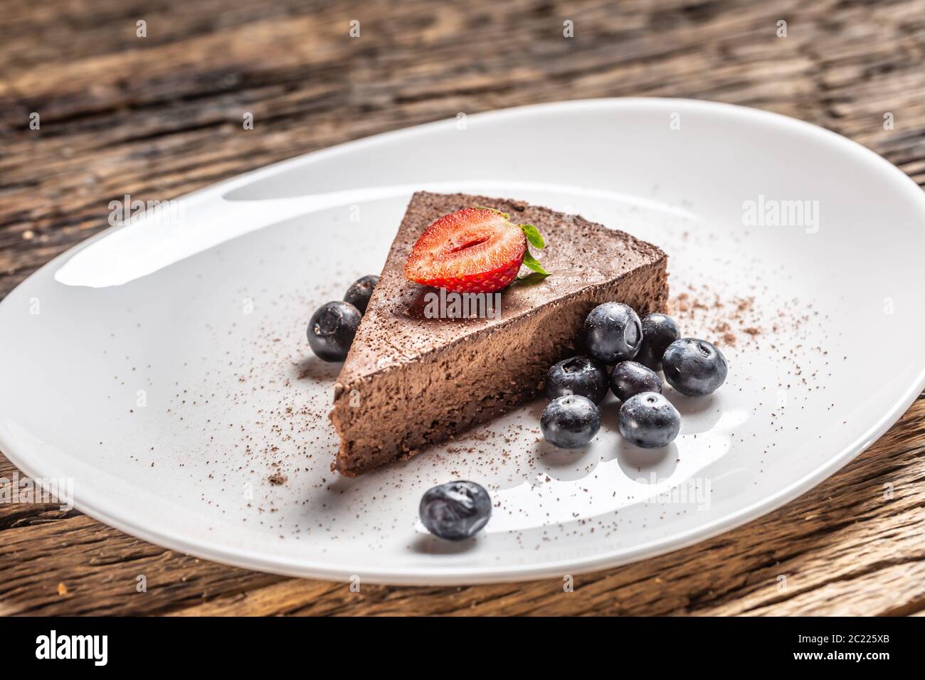 Fetta triangolare di torta di mousse al cioccolato con mirtilli e fragole Foto Stock