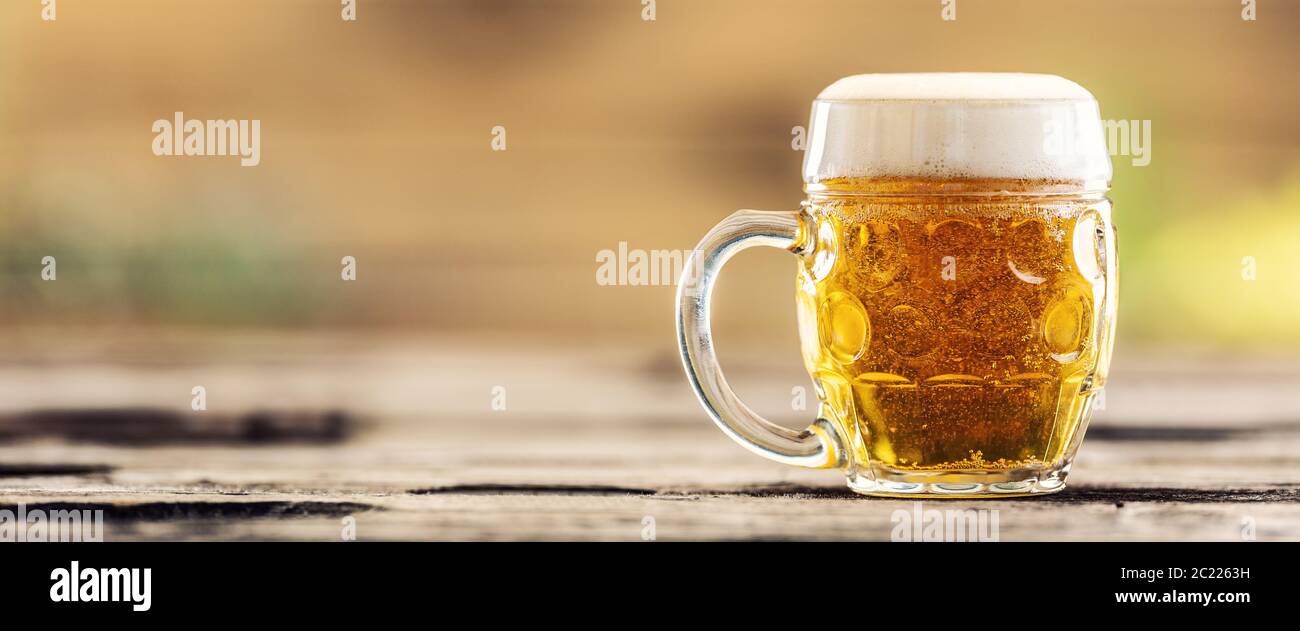 Tazza di birra con una birra fresca alla spina su un tavolo esterno Foto Stock