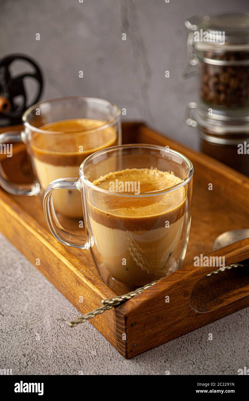 Bevanda a base di caffè ghiacciata Dalgona su sfondo vassoio di legno. Caffè istantaneo o espresso in polvere con zucchero e acqua calda. Caffè con latte latte Foto Stock