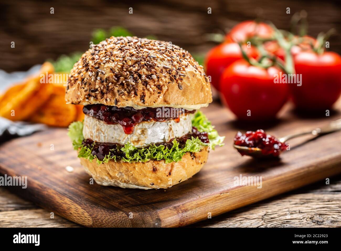 Hamburger vegetariano con camembert e salsa di mirtilli su una tavola rustica in legno Foto Stock