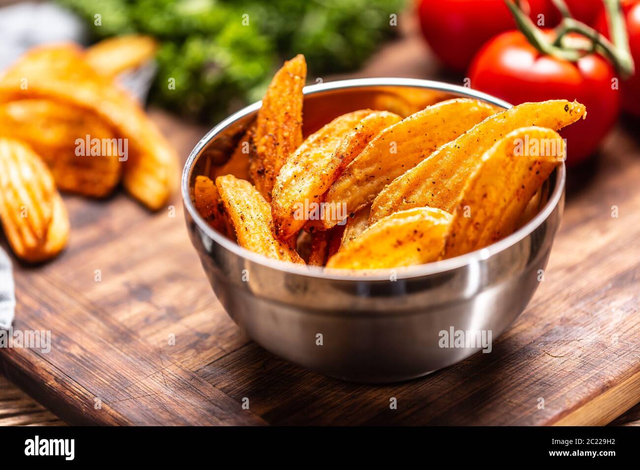 Dettaglio di spicchi di patate al forno speziati in un recipiente in metallo Foto Stock