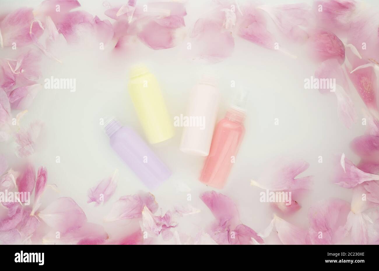 Tubi cosmetici con pony rosa in acqua di latte. Centro benessere e  trattamento benessere con petali di fiori in bagno con latte. Il concetto  di purezza Foto stock - Alamy