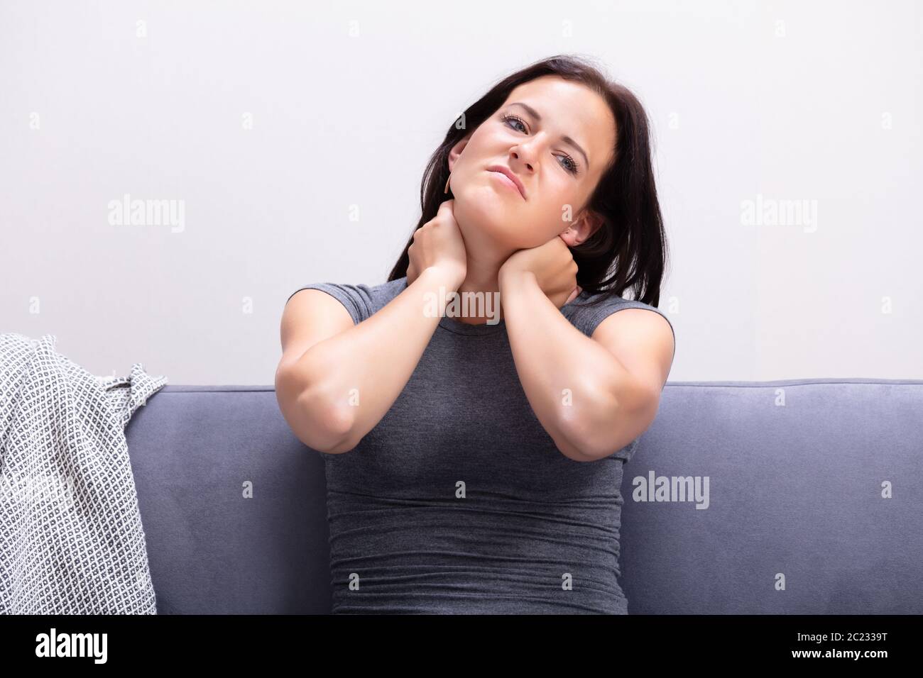 Ritratto di giovane donna che soffre di dolori al collo a casa Foto Stock