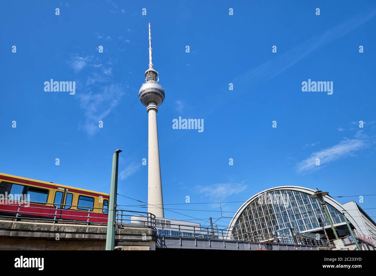 La torre della televisione di Berlino con un treno dei pendolari entrando nella stazione ferroviaria Foto Stock