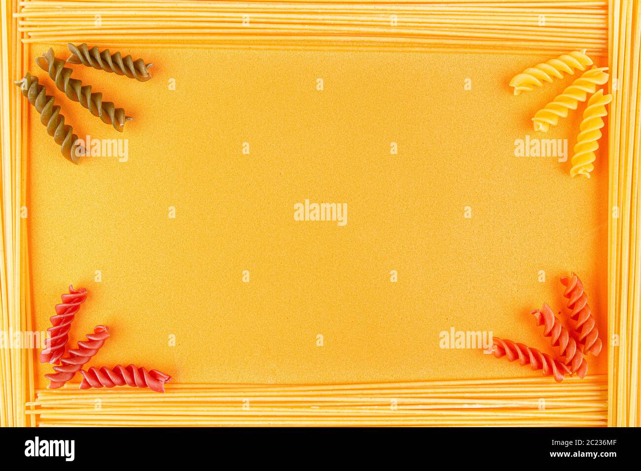 Cornice in pasta spaghetti su fondo in schiuma arancione, colorati  maccheroni a spirale negli angoli Foto stock - Alamy