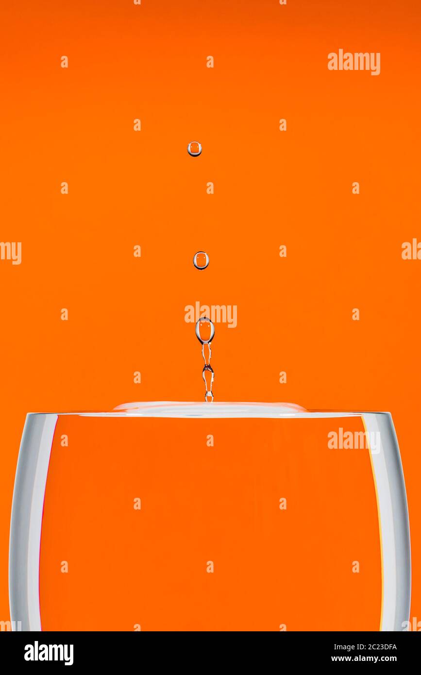 Immagine di uno studio interno di una caduta d'acqua ad alta velocità su uno sfondo arancione Foto Stock
