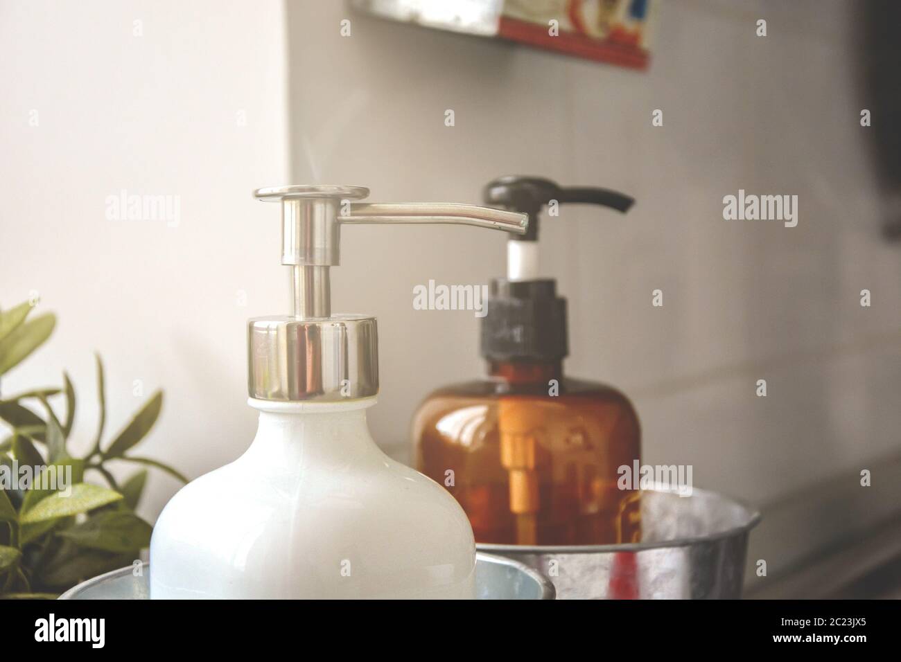 Due dispenser di sapone in una sala luminosa con luce naturale. Foto Stock