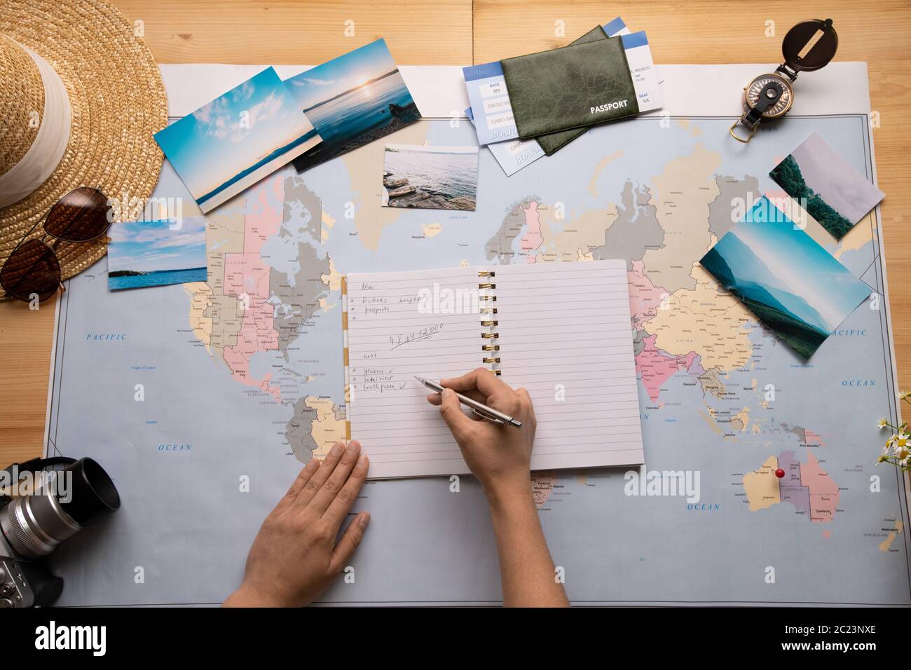 Vista sopra il viaggiatore irriconoscibile che compone la lista di controllo nel diario durante la pianificazione del viaggio Foto Stock