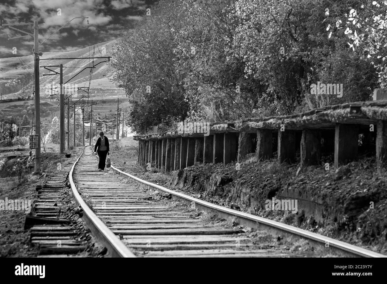 Donna che cammina su una vecchia strada ferroviaria dall'era sovietica, ad Atskuri, Georgia Foto Stock