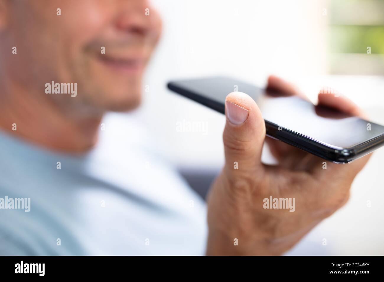 Close-up di una barba uomo con funzione di riconoscimento vocale sul proprio telefono cellulare contro uno sfondo bianco Foto Stock